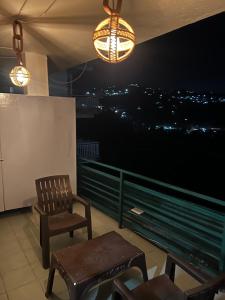 a balcony with a chair and a table and lights at Pine & Peaks in Patta