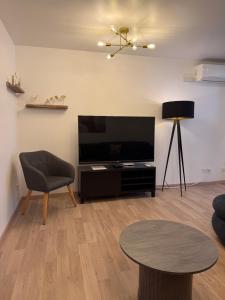 a living room with a flat screen tv and a table at Gîte Région des Lacs - SPA et Sauna Privatif in Orgelet