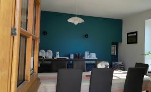 a dining room with a blue wall and a table and chairs at La Rivetière in Courcemont