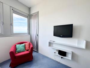 a living room with a red chair and a television at Nuvola 24 - Casa Vacanza in Rimini
