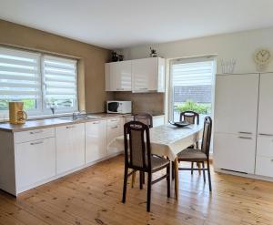 a kitchen with white cabinets and a table and chairs at Ferienwohnung Gartenblick in Fuhlendorf