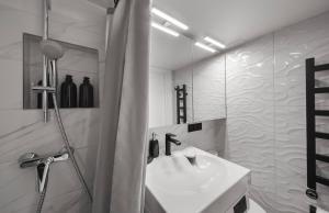 a white bathroom with a sink and a shower at Cosy apartment in Vilnius