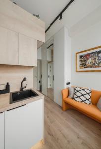an open kitchen and living room with an orange couch at Cosy apartment in Vilnius
