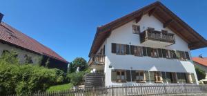 a white building with wooden balconies and a fence at Lake&Mountain Apartments in Andechs
