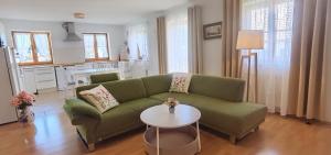 a living room with a green couch and a table at Lake&Mountain Apartments in Andechs