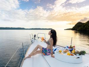 a woman sitting on a boat with a drink at Palau Mangrove Hotel in Koror