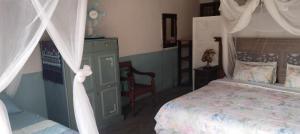 a bedroom with a canopy bed and a chair at Shongili Island Lodge in Vila Praia Do Bilene