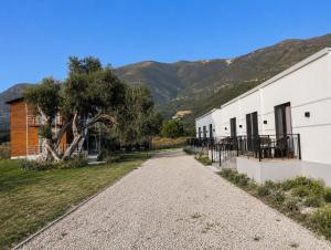 a gravel road next to a building with mountains in the background at PRIAM Beach Borsh in Borsh