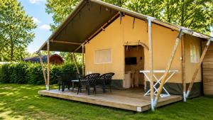 a tent with chairs and a table on a deck at Camping ’t Veld in Rheeze +6 photos