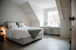 ein weißes Schlafzimmer mit einem Bett und einem Fenster in der Unterkunft Between Flanders Walls in Ypern