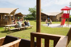 a group of people sitting at picnic tables in a park at Camping ’t Veld in Rheeze
