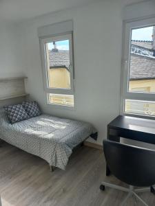 a bedroom with a bed and a desk and two windows at Casa de la Soledad 3 in Lugo