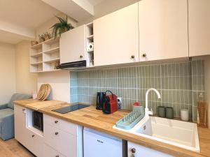 a kitchen with white cabinets and a sink and a counter at Le Stervin in Villefranche-sur-Saône