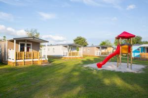 a playground with a slide in a yard with houses at Camping ’t Veld in Rheeze