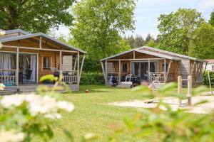 two cottages in the yard with a person sitting on the porch at Camping ’t Veld in Rheeze