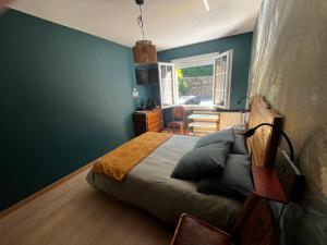 a bedroom with a bed with blue walls and a window at Chez Amélie in Crémieu