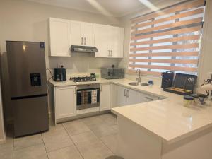 a kitchen with white cabinets and a stainless steel refrigerator at Dreams Apartments in Victoria Falls