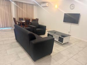 a living room with a black couch and a table at Dreams Apartments in Victoria Falls