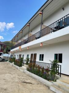 a white building with balconies on the side of it at Malee Guesthouse in Ban Rak Thai