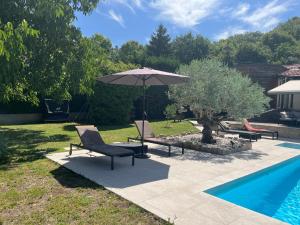 a patio with two chairs and an umbrella next to a pool at Chez Amélie in Crémieu