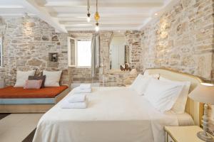a bedroom with a large bed and a stone wall at Corfu Breeze Liston Apartments in Corfu