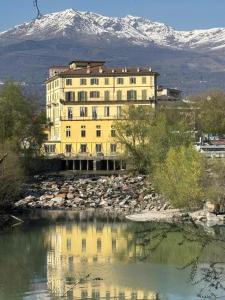 a large yellow building next to a body of water at Station -Mansarda in posizione strategica, vista panoramica, letto king size e clima in Ivrea
