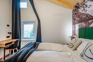 a bedroom with a bed and a desk and a window at Alpine Lodge Green by Tss - Downtown, classy in Levico Terme