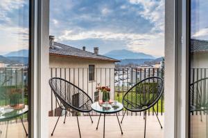 a patio with two chairs and a table on a balcony at Alpine Lodge Green by Tss - Downtown, classy in Levico Terme