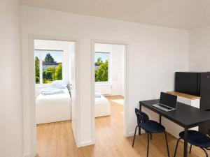 a bedroom with a desk and a bed with a laptop at CityNest Apartment Mülheim in Mülheim an der Ruhr