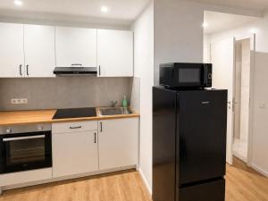 a kitchen with a black refrigerator and a sink at CityNest Apartment Mülheim in Mülheim an der Ruhr