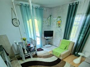 a living room with a green chair and a television at Eco Bay Montenegro in Donji Morinj