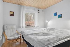 a bedroom with a bed and a chair and a window at 30640-Odder-Magevej-7 in Odder