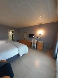 a bedroom with a bed and a desk and a television at Matsapha Hotel in Mahlanya