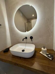 a bathroom sink with a round mirror on a wooden counter at Salsedo Seaside Rooms in Kanali +25 photos