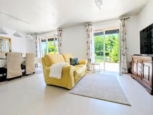 a living room with a yellow chair and a table at VILLA climatisée - 4 étoiles - 75 m2 avec Jardin pour 3 personnes - à 10 min de Besançon in Dannemarie-sur-Crête