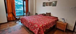 a bedroom with a bed with a red comforter and a window at Anandam in Mashobra