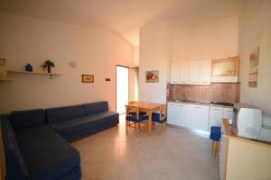 a living room with a couch and a table and a kitchen at Villaggio Sa Ventana in Badesi