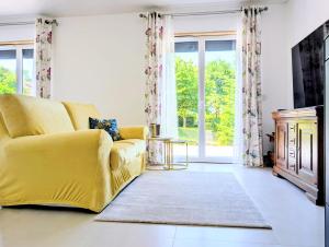 a yellow couch in a living room with a large window at VILLA climatisée - 4 étoiles - 75 m2 avec Jardin pour 3 personnes - à 10 min de Besançon in Dannemarie-sur-Crête +20 photos