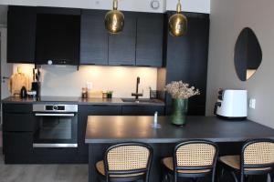 a kitchen with black cabinets and a table with chairs at Moderne toppleilighet i Bergen in Bergen