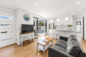 a living room with a couch and a table at Waves Beach House in Marcoola