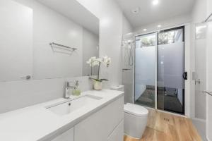 a white bathroom with a sink and a toilet at Waves Beach House in Marcoola +14 photos