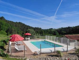 a swimming pool with two chairs and a red umbrella at B&B Angueur in Montrem