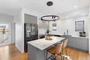 a kitchen with a large island with two bar stools at La Mer in Marcoola in Marcoola