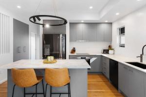 a kitchen with a large island with two bar stools at La Mer in Marcoola in Marcoola +35 photos