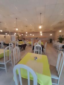a dining room with tables and white chairs at Matsapha Hotel in Mahlanya