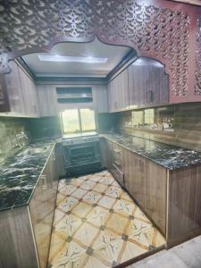 a kitchen with wooden cabinets and a tile floor at Stylish Apartment in Khaira Gali