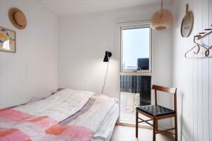 a bedroom with a bed and a chair and a window at 1115-Ringkobing-Nordsovej-466 in Søndervig