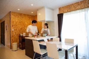a man and woman standing in a kitchen preparing food at Win Village in Sasebo