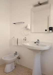 a white bathroom with a sink and a toilet at Hostal Lara in Llança