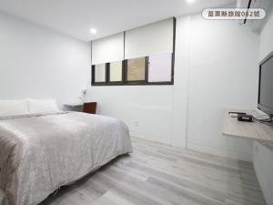 a bedroom with a bed and a flat screen tv at WE Hotel in Miaoli